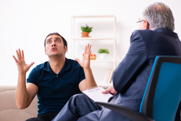 Young man visiting old male psychologist