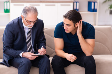 Young man visiting old male psychologist