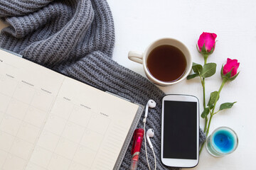 notebook planner ,hot coffee ,mobile phone and knitting wool scarf of lifestyle woman for business work in winter season on background wooden