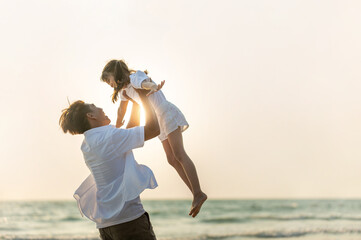 Happy Asian Family father carrying little cute daughter with smiling face on the beach in summer sunset. Dad and child girl enjoy and having fun together in outdoor lifestyle holiday vacation travel.