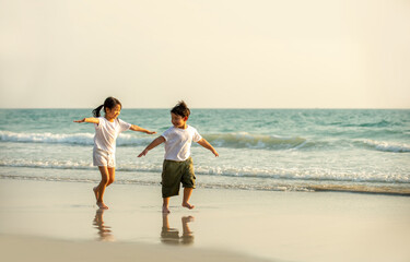 Happy Asian family little brother and sister running and playing together on the beach at summer...