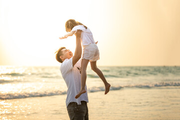 Happy Asian Family father carrying little cute daughter with smiling face on the beach in summer...