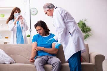 Obraz premium Two doctors visiting sick young man at home