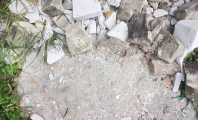 concrete floor with a plant and broken stones. background for words and ads with an empty space around plants and stones, block, brick concrete wall