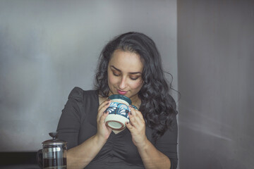 beautiful Mexican woman smelling coffee from a Mexican cup