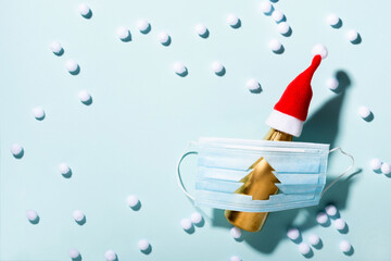 New normal Christmas concept. Protective mask with Christmas tree hole and champagne in Santa hat on blue background