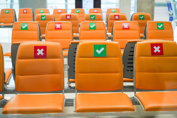 Row of empty bench chair seats in public transportation terminal with social distancing guidance during Coronavirus pandemic. Covid-19 safety advice to prevent virus spread concept.