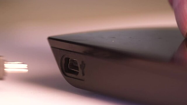 Close up of a man's hand hand plugging in external USB hard drive