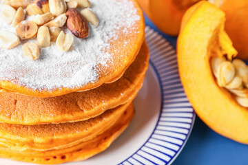 Plate with tasty pumpkin pancakes on color background, closeup