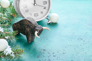Figurine of bull, clock and New Year decor on color background