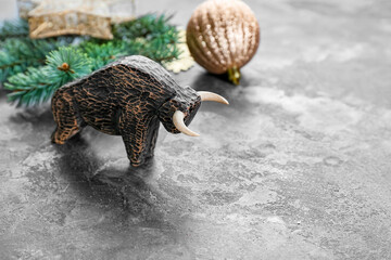 Figurine of bull and New Year decor on grey background