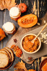 Autumn composition with tasty pumpkin jam on wooden background