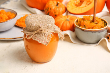 Jar of tasty pumpkin jam on table