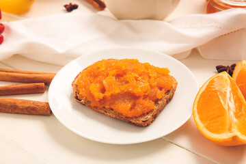Plate with tasty bread and pumpkin jam on table
