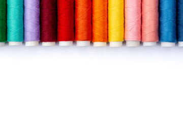 Colorful sewing threads on white background, top view. Spools of thread in different colors.