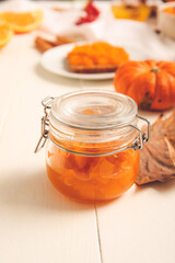 Jar of tasty pumpkin jam on table