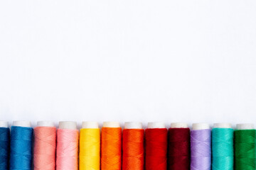 Colorful sewing threads on white background, top view. Spools of thread in different colors.