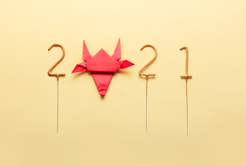 Figure 2021 with origami bull as symbol of the year on color background