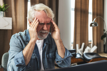 Elderly man holding his head experiencing headache and stress due to pressure