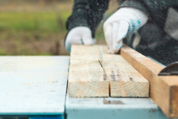 Daylight. machine for sawing wood. The master hands the board. Close-up.