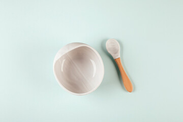 Grey silicone dishware plate and spoon on background. Serving baby, first feeding concept. Flat lay