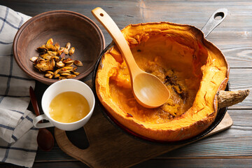 Pumpkin in a skillet with seeds and honey on a light table