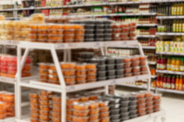 Canned food in jars on the shelves in the supermarket, store interior. Blurred.