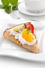 Crepes with soft cream, strawberries, kiwi, oranges and mint