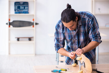 Young man repairing skateboard at workshop