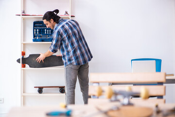 Young man repairing skateboard at workshop