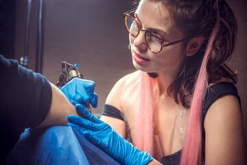 Professional tattooer making tattoo in salon studio
