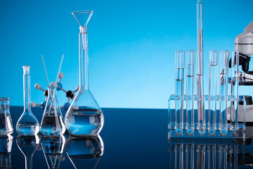 Science concept. Laboratory equipment composition. Test tubes and microscope on blue background.