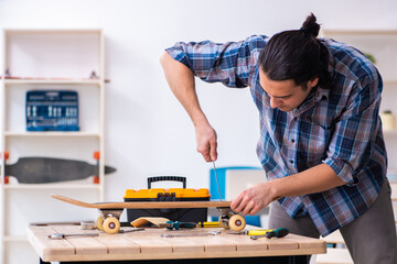 Young man repairing skateboard at workshop