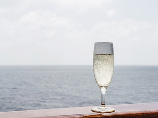 Beautiful glass with a drink on the background of sea waves and sun rays. Top view, close-up. Concept of leisure and travel