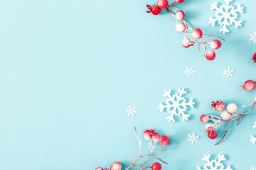 Christmas or winter composition. Snowflakes and red berries on blue background. Christmas, winter, new year concept. Flat lay, top view