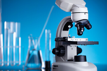 Science concept. Laboratory equipment composition. Test tubes and microscope on blue background.