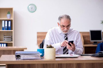 Old male employee suffering from radiculitis at workplace