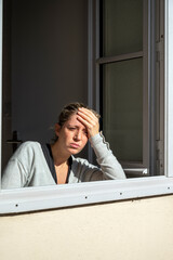 Femme triste et confinée prenant le soleil à la fenêtre ouverte de sa maison
