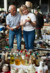 Glad man and woman choosing interesting souvenirs at traditional flea market. High quality photo