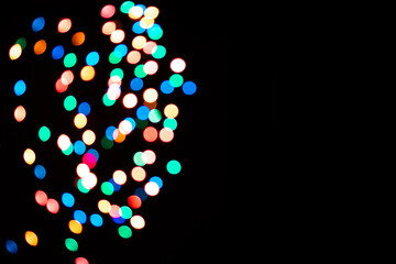 Multi-colored glares side on a black background with room for copyspace text. Festive New Year's background bokeh