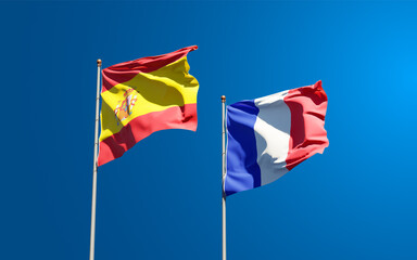 Beautiful national state flags of France and Spain together at the sky background. 3D artwork concept.