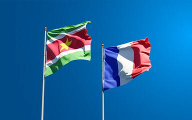 Beautiful national state flags of France and Suriname together at the sky background. 3D artwork concept.
