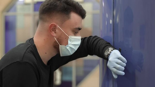 Young man in blue medical mask coughs hard and tries to catch his breath in the subway. Keep yourself and others safety.