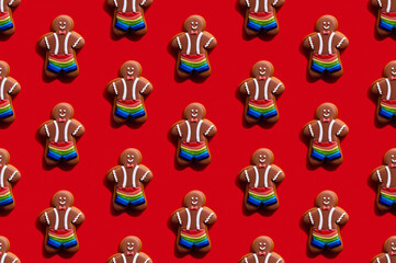 Fototapeta premium Lgbt pride. Red seamless background. Diversity tolerance. Bakery food art conceptual ornament. Happy African gay gingerbread man biscuit in rainbow shorts minimalist composition isolated on bright.