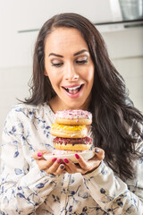 Beautiful girl considers eating donuts piled up on a plate she hold in front of her