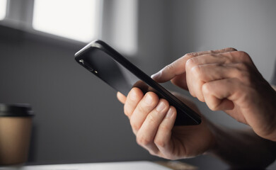 Young man using mobile phone indoors.	Male hands with smartphone at home closeup