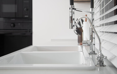New modern faucet and kitchen room sink close up.