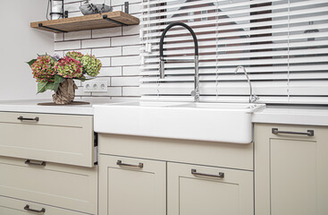 White kitchen furniture near the washbasin in white color in the style of milimalism.