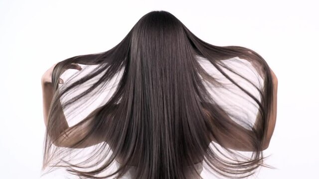 Woman moves long hair. Rear view. Girl shakes long straight hair. Female model is fluttering hair.  Slow motion footage. Rear view.