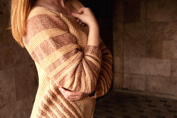 Young beautiful woman in a cozy beige sweater spends time outdoors. Lifestyle portrait of female